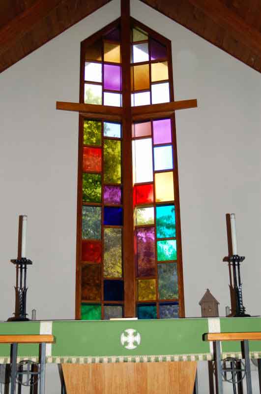 St. Paul's sanctuary: large cross with stained glass with altar with candles.
